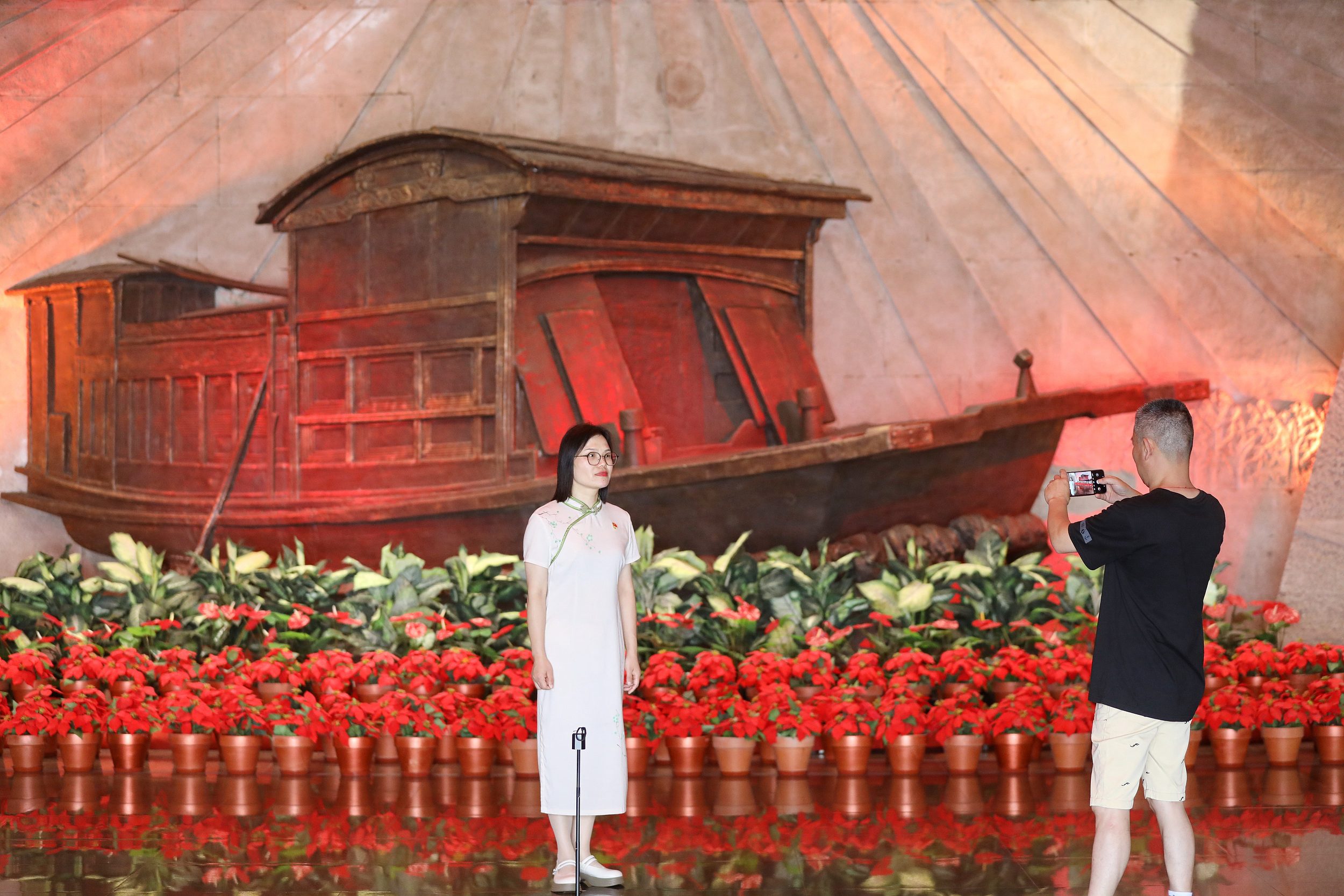 2025年6月24日,浙江嘉興,游客在南湖革命紀(jì)念館與紅船雕塑合影。(圖片來源:視覺中國)